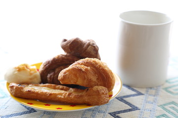 Breakfast of milk and mini bread. Croissant, chocolate croissant, banana bread and green soybean bread.