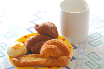 Breakfast of milk and mini bread. Croissant, chocolate croissant, banana bread and green soybean bread.