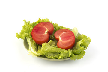 Cut tomato on a green salad leaves on a green ceramic dish