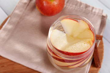 Glass of apple cider with fruits and cinnamon on table close up
