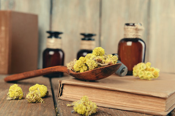 Old books with dry flowers and bottles on table close up