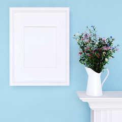 Mock up poster and wildflowers on a dresser with blue wall
