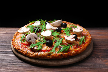 Tasty pizza with vegetables and arugula on black background
