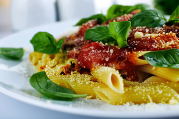 Pasta with tomato sauce and basil on table close up
