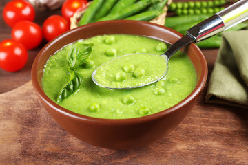 Tasty peas soup and cherry tomatoes on table close up