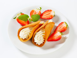Cone-shaped gingerbread cookies with whipped cream and strawberries
