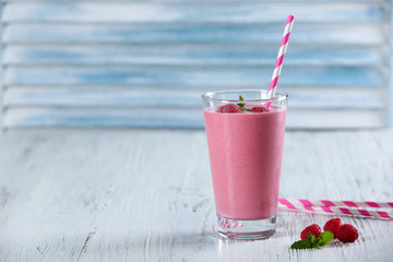 Glass of raspberry milk shake with berries on wooden background
