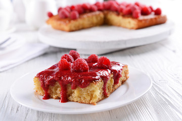 Fresh pie with raspberry jam in white saucer on wooden table, closeup
