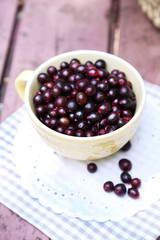 Red gooseberry in cup on wooden table close-up outdoors