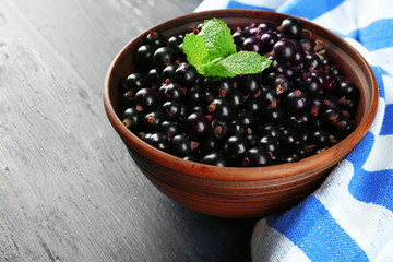 Ripe blackcurrant in bowl on wooden background