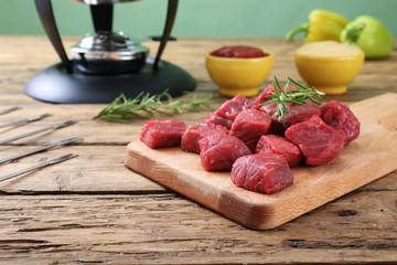 carne cruda manzo tagliato a cubi su tagliere sfondo legno rustico