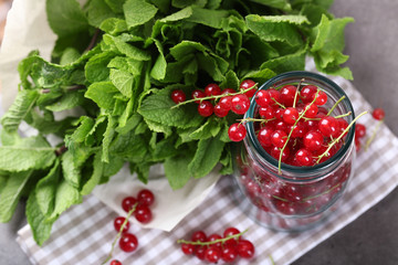 Fresh red currants in jar with mint on table close up