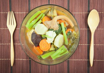 Fresh hot vegetable soup and spoon on wood