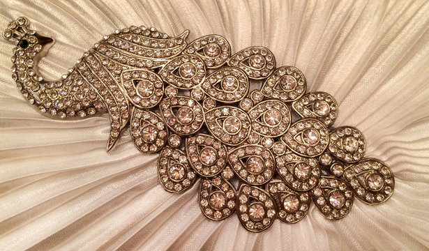 Close up of Jewelry in Peacock Design on White Textile Pattern Texture Background