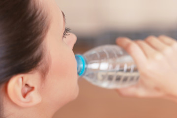 Young sportswoman drinking water after training 