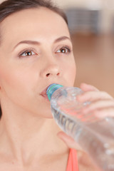 Young sportswoman drinking water after training 