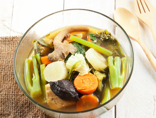 Fresh hot vegetable soup and spoon on wood