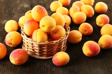 Ripe apricots in wicker basket  on wooden background