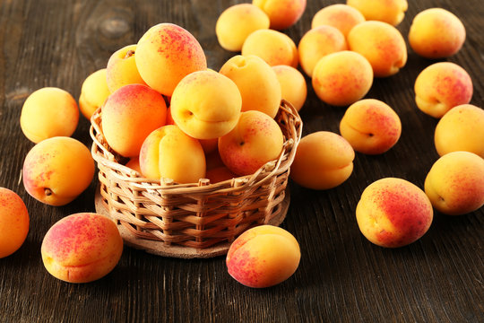 Ripe apricots in wicker basket  on wooden background