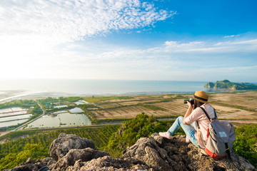 Hiker woman with camera enjoy the view at sunrise mountain peak