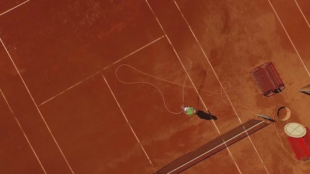 Young female tennis player having a training lesson on a red clay court