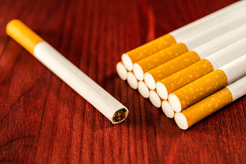 Group of cigarettes with cigarette lying near on the table