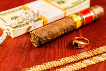Expensive Cuban cigar and a pack of dollars with gold chain, gol - obrazy, fototapety, plakaty