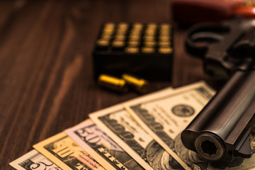 Revolver with a bundle of money on a wooden table