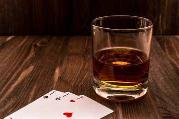 Glass of whiskey and playing cards on the wooden table