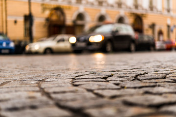 City central square paved with stone after a rain on which riding car. View from the pavement level