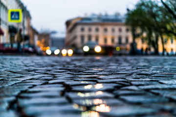 City central square paved with stone after a rain, headlights fr