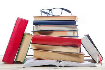 Stack of books and glass on wooden table isolated on white background. Back to school. Copy space