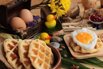 Sweet waffles and fresh milk with jam and egg heart.
