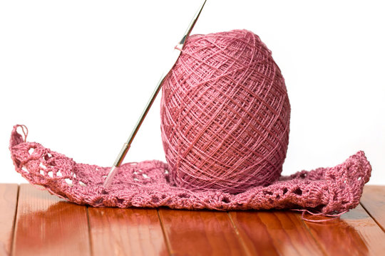 Pink yarn and needles on a chair in isolated background.