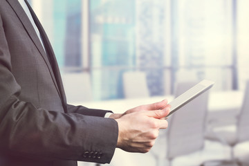 Close-up of side view of a businessman who is browsing on his tablet. Office view with Singapore panoramic view. Toning filter.