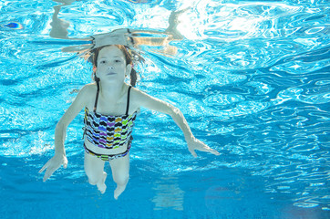 Obraz na płótnie Canvas Child swims in pool underwater, happy active girl has fun in water, kid sport 