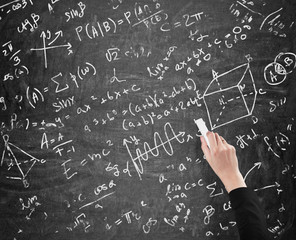 A woman's hand is writing math calculations on black chalk board. Analyst.