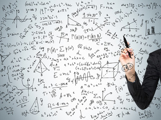 Woman's hand is pointing out the complicated math calculations. Math formulas are written on the...