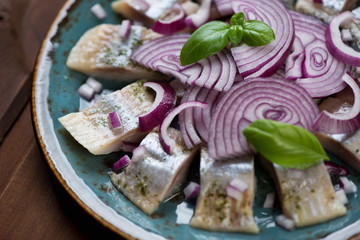 Close-up of sliced herring fillet with red onion and green basil