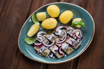 Sliced herring fillet served with red onion and boiled potato