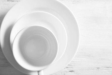 White plates and cups on a light wooden background