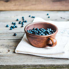Fresh blueberries in pottery on gray wooden background, summer,