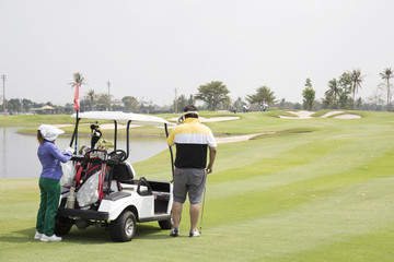 Golfer , Caddie and golf cart on the fairway