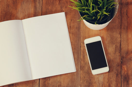 image of open notebook with blank pages next to smartphone
