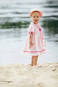 little girl standing on the coast of river