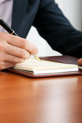 Closeup of a businessman writing on agenda