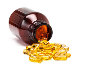 fish oil capsules spilling out from brown glass bottle