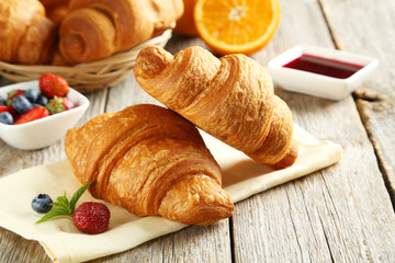 Fresh tasty croissants with berries on grey wooden background