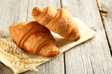 Tasty croissants with spikelets on grey wooden background
