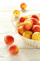 Fresh apricots in basket on a white wooden background